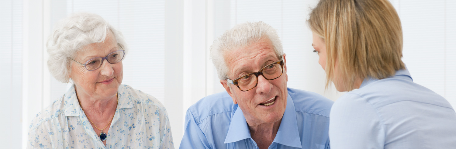 Elderly couple and nurse talking.